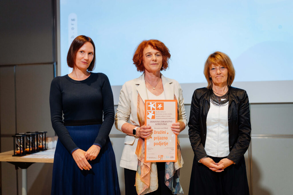 3 ženske, na sredini strokovna vodja drži prejeti certifikat